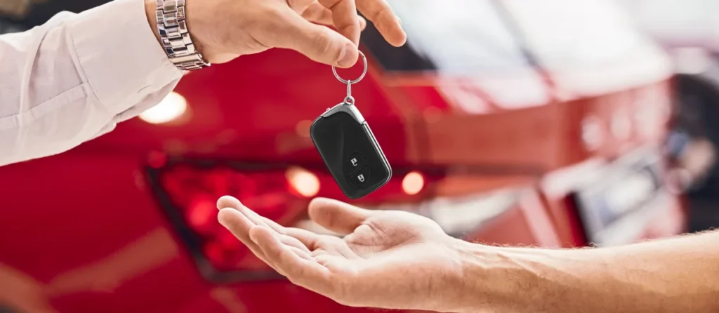A person handing over a car key fob to another person.