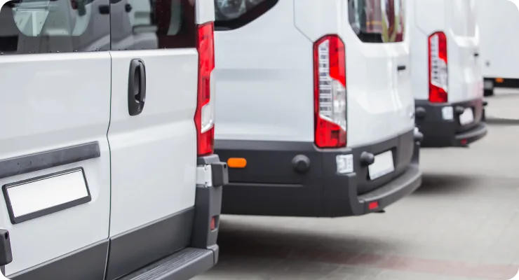 A line of white commercial vans, representing a focus on fleet service and maintenance.