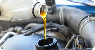 A mechanic's hands pouring fresh, golden motor oil into a car's engine.