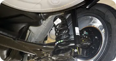 A detailed shot of a car's axle and shock absorber components, highlighting suspension service.