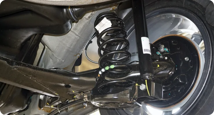 A detailed shot of a car's undercarriage showing a clean, high-performance suspension or strut assembly.