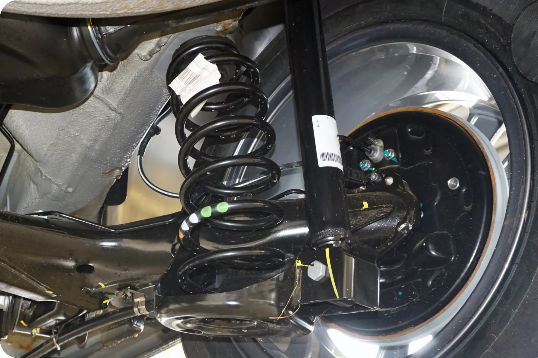 A detailed, close-up shot of a car's rear suspension coil spring and shock absorber assembly.